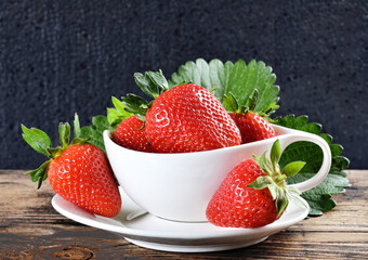 Fresh strawberry in a bowl on a dark wooden background