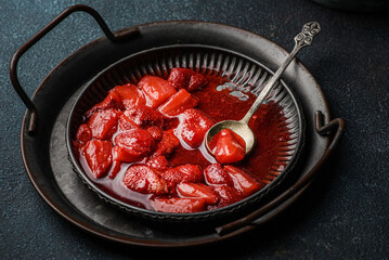 Fresh strawberry sauce on a plate on a dark background