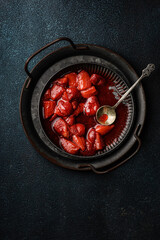 Fresh strawberry sauce on a plate on a dark background