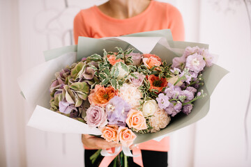 Very nice young woman holding big and beautiful bouquet of fresh hydrangea, roses, matthiola, carnations in pastel peach and purple colors, cropped photo, bouquet close up - Powered by Adobe
