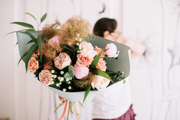Very nice young woman holding big and beautiful bouquet of fresh brunia, roses, cotinus, peony, eucalyptus in white and pink colors, cropped photo, bouquet close up