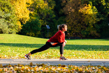 Young woman warming up and stretching before running in park.