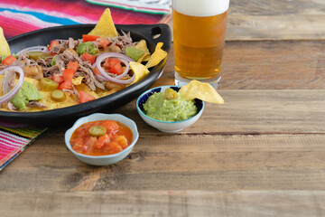 tray with nachos and beer over wooden table.