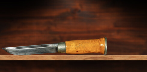 Close-up of an old hunting knife made in Norway, on a wooden shelf or table with copy space.