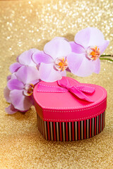 gift box in the form of heart and an orchid on a golden background
