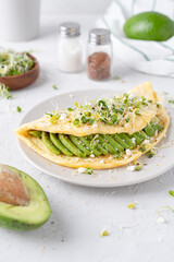 Nice breakfast with avocado. Omelet with microgreens. Gray background with breakfast.