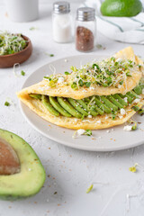 Nice breakfast with avocado. Omelet with microgreens. Gray background with breakfast.
