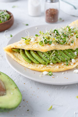 Nice breakfast with avocado. Omelet with microgreens. Gray background with breakfast.