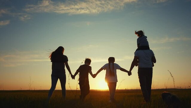 people in the park silhouette. happy family kid dream holiday concept. friendly lifestyle family holding hands walking dog at sunset in the park silhouette. big family silhouette walk in the park