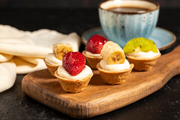Fruit tartlet. Strawberry, kiwi and banana tartlet on a dark background. close up
