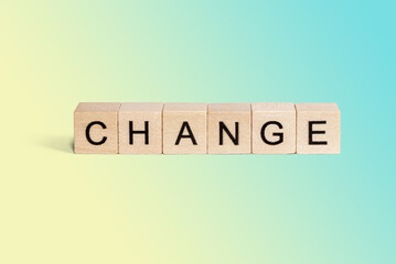 Wooden cubes with the word Change on a blue and yellow background with copy space.