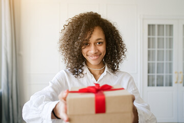 Excited african american young woman present gift box with ribbon. Family lifestyle, valentine's day, birthday holiday concept