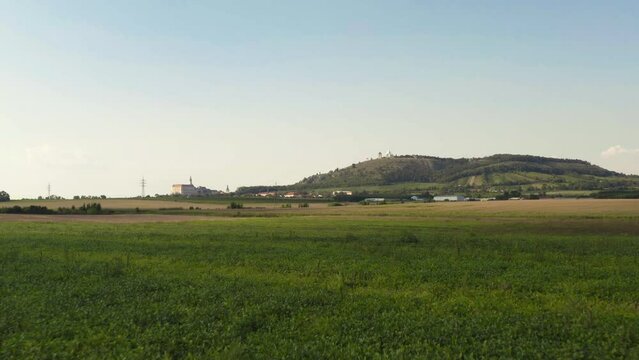 Fields below Svatý Kopeček hill in Moravia landscape, dolly drone shot.