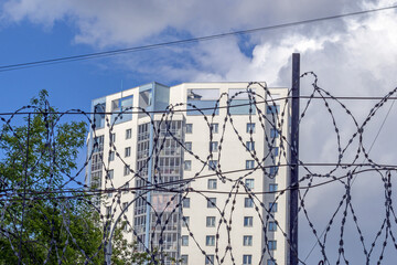 Multi-storey residential building behind barbed wire on a spring day