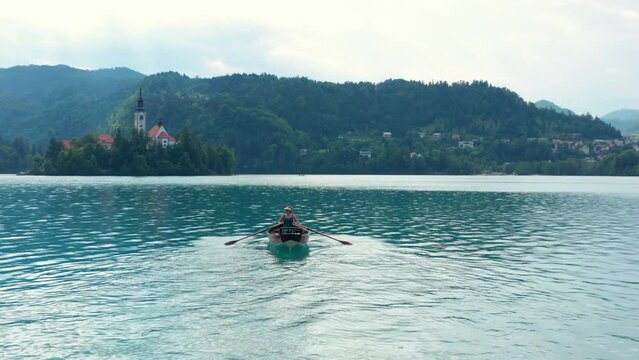 Woman Rowing Her Boat In The Middle Of The Bled Lake Towards Bled Island In Slovenia. - aerial