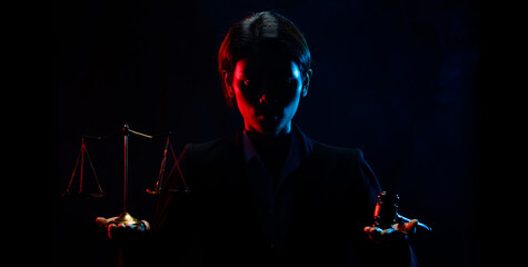 Legal Judge show both hands of Balance Scale and Justice Hammer. Dark background of blue red