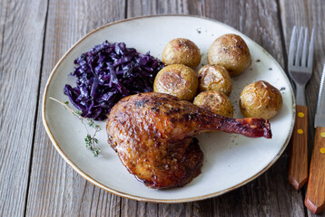 Baked duck leg with potatoes and red cabbage.