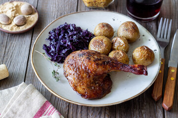 Baked duck leg with potatoes and red cabbage.