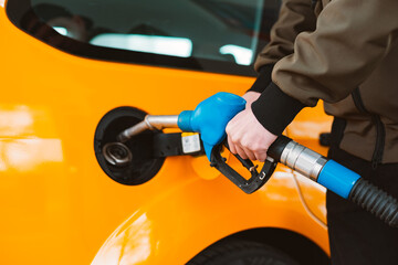 Unrecognizable man refueling car from gas station filling benzine gasoline fuel in car at gas station. Petrol high prices concept