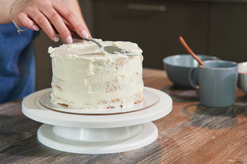 female hands cover a round cake with butter cream. making a homemade cake. DIY baking