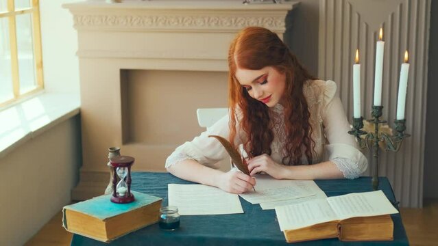 Medieval red-haired woman writer holds pen feather quill in hands, sits at table writes letter on sheet paper. Vintage dress ancient room antique candlestick, old books. Girl smiling student studying