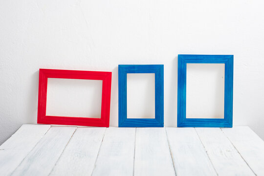 empty red and blue picture frames on white wooden table