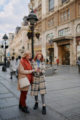 A grandmother and her grandchild standing on the street and reading messages on the phone.