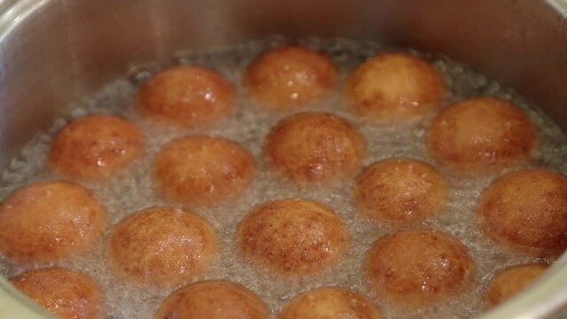 Dough balls float and fry until golden brown in boiling oil close-up