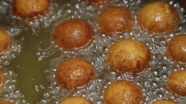 Traditional dessert balls of cottage cheese dough are deep fried in boiling oil until golden brown turning from side to side