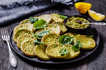 spinach pancakes on black plate with basil pesto