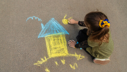 Children draw the Ukrainian flag house on the pavement. Selective focus.