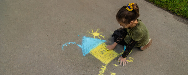 Children draw the Ukrainian flag house on the pavement. Selective focus.
