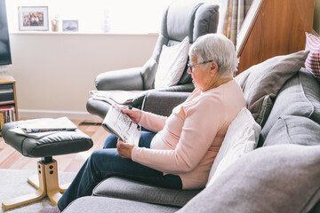 Old senior woman, 80s adult, grandmother, making crossword puzzles in her living room sitting on...