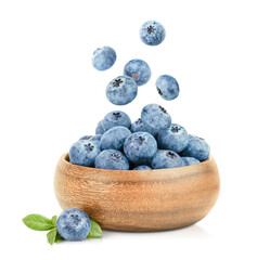 fresh blueberries in a wooden plate and berries falling into it on a white isolated background