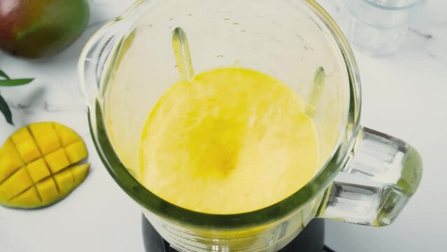 Cooking mango smoothie or milkshake in blender with splashes. High angle view. Healthy drink concept. 4k video