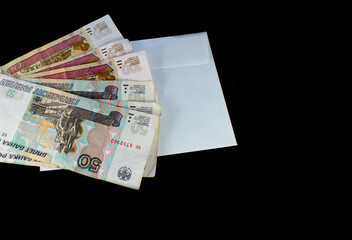 Russian rubles in a white envelope on a black background. The concept of the 