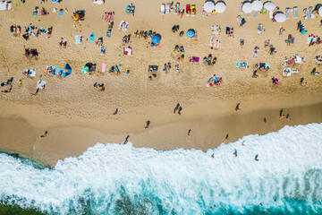 aerial shooting from a drone on a sandy beach with people sunbathing and relaxing. Flat view of the shore and turquoise waves of the surf and people bathing