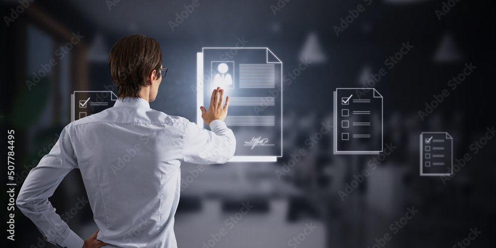 Poster Back view of attractive young european businessman using abstract digital documentation hologram on blurry office interior background. Signature and digital transformation concept. Double exposure.
