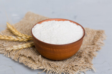 Flat lay of Wheat flour in wooden bowl with wheat spikelets on colored background. world wheat crisis