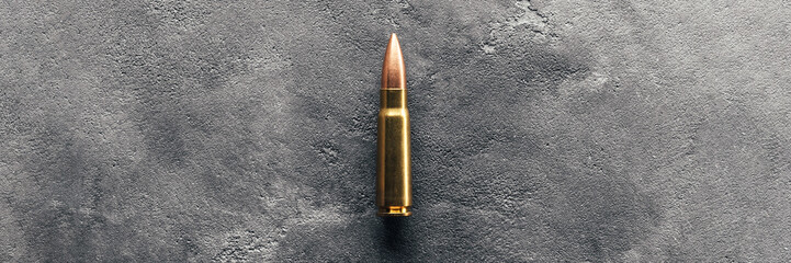 Bullet on gray background banner with copy space. Cartridge 7.62 caliber for Kalashnikov assault rifle. Panoramic web header. Wide screen wallpaper - obrazy, fototapety, plakaty