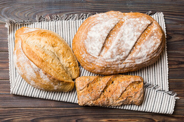 Assortment of freshly baked bread with napkin on rustic table top view. Healthy unleavened bread. French bread
