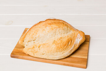 Freshly baked bread on cutting board against white wooden background. perspective view bread with copy space