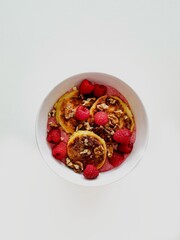 Homemade cheesecakes wit fresh raspberries and strawberry sauce served with walnuts