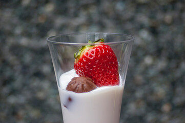 Copa de yogur con fresa y bombón de chocolate para postre.