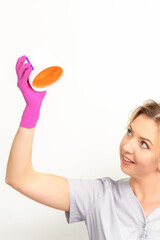 Portrait of a female caucasian beautician holding a jar of sugar paste for sugaring wearing pink gloves on white background