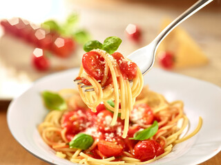 Nudeln Parmesan Tomatensauce auf Gabel über einem Spaghettiteller Tomaten unscharf im Hentergrund - obrazy, fototapety, plakaty