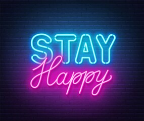 Stay Happy neon quote on a brick wall.