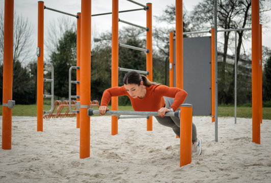 Strong fit sporty woman doing push ups at city park outdoor gym. Fitness calisthenics workout.