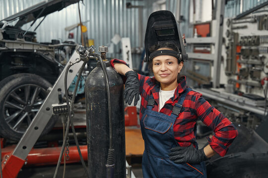 Female auto mechanic standing in car service garage
