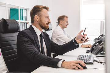 Employees of the company work at computers in the office. Interaction in the process of work and problem solving. Workplace in modern business space